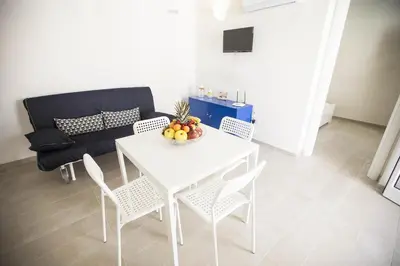 a white table and chairs in a living room with a couch at Villa Del Mare in Alcamo Marina