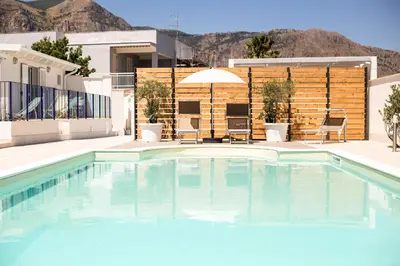 a pool with blue water in front of a house at Villa Del Mare in Alcamo Marina