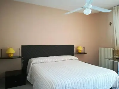 a bedroom with a bed with a white blanket and a ceiling fan at Kairos B&B in San Giuseppe Jato
