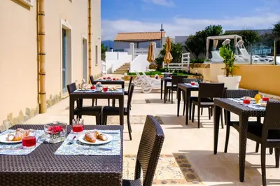 a patio with tables and chairs with food on it at Hotel Baglio Di Scopello in Scopello
