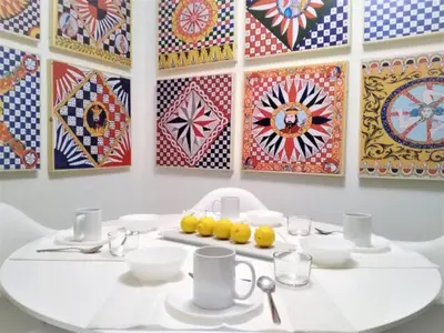 a white table with plates and cups and paintings on the wall at COLORI di PALERMO in Palermo