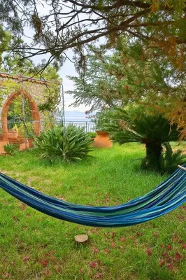 a blue hammock in the grass in a yard at Maison de Soleil in Scopello
