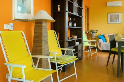 a living room with yellow chairs and a lamp at Maison de Soleil in Scopello