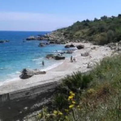 a beach with people on the sand and the ocean at Maison de Soleil in Scopello