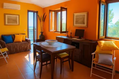 a living room with orange walls and a table and chairs at Maison de Soleil in Scopello