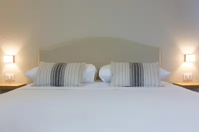 a bedroom with a bed with two pillows and two lamps at Mondello Martini in Mondello