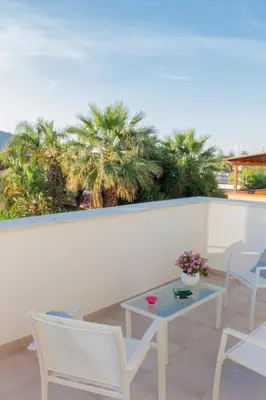 a balcony with chairs and a table and palm trees at Mondello Martini in Mondello
