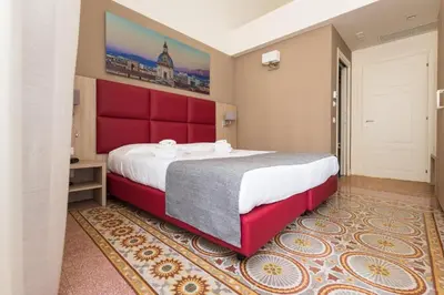 a small bedroom with a bed and a red chair at Belmonte102 Esclusive Suites in Palermo