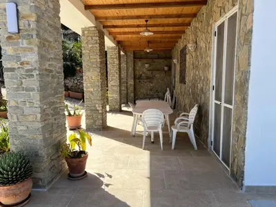 a patio with a table and chairs on a stone wall at Suite Panoramic in Porticello