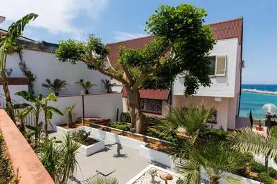 a house with a tree in front of the ocean at Vero Sicily - Villa San Giorgio in Cinisi