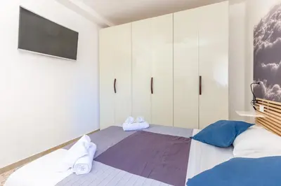 a bedroom with a bed with a tv and white cabinets at Maison Brigitte - Solemar Sicilia in Santa Flavia