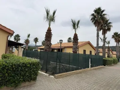 a fence with palm trees in front of a house at Residence Hydria in Campofelice di Roccella