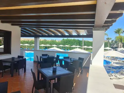 a restaurant with tables and chairs and a swimming pool at Residence Hydria in Campofelice di Roccella