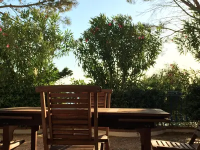 a wooden table and chair sitting next to a table and trees at villa Anna Silvia Makari fiction rai 1 Casa Saverio La Manna in San Vito lo Capo