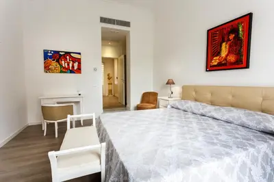 a white bedroom with a large bed and a table at Porta Maqueda in Palermo
