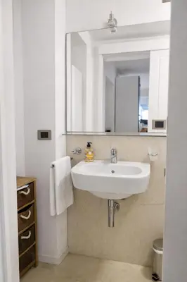 a bathroom with a white sink and a mirror at Palazzo Moncada Apartment in Palermo