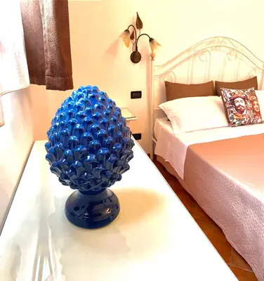 a blue vase sitting on a table next to a bed at Il Cortile in San Vito lo Capo