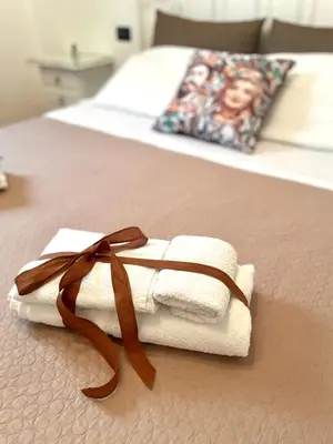 a pile of towels on a bed with a brown ribbon at Il Cortile in San Vito lo Capo