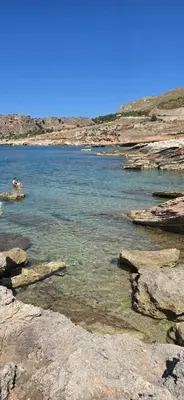 a person swimming in a body of water with rocks at Al Civico 365 in Castelluzzo