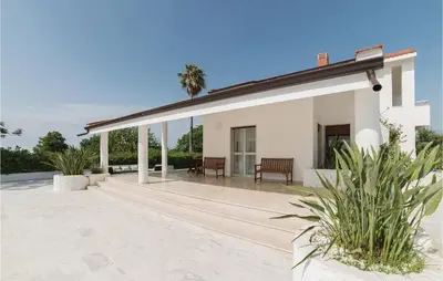 a white house with a patio and palm trees at Villa Delle Sterlizie in Valguarnera