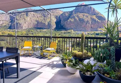 a patio with a table and chairs and a mountain at Gebel Grin in Palermo