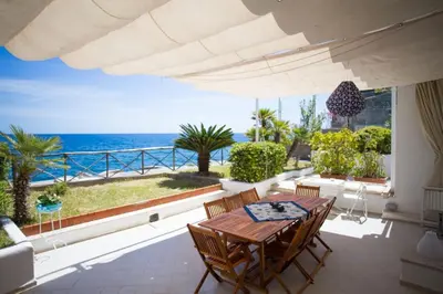 a patio with a table and chairs and the ocean at Villa sul mare in Palermo