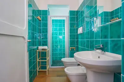 a green tiled bathroom with a sink and a toilet at Casa di Cri in San Vito lo Capo