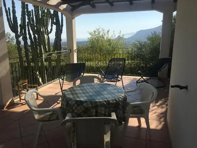 a bedroom with a bed and two pink chairs at Villa Nadia con splendida vista mare in Castellammare del Golfo