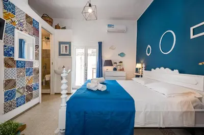 a blue bedroom with a white bed and blue walls at Le Maioliche in Castellammare del Golfo