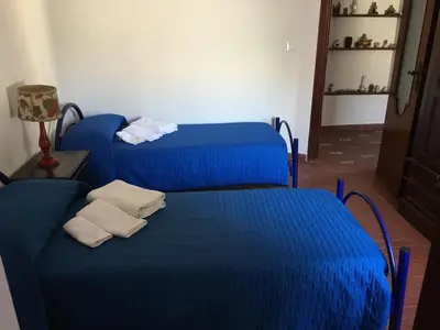 two beds with blue sheets in a room at Villino Fraginesi in Castellammare del Golfo