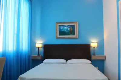 a blue bedroom with a bed with two lights on at La Maison del Sole in Palermo