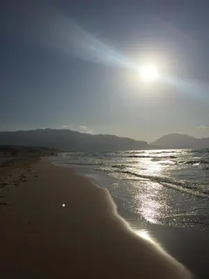 a beach with the sun shining on the water at Profumo di Mare 1 in Alcamo Marina