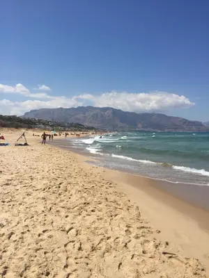 a beach with people walking on the sand and the ocean at Profumo di Mare 1 in Alcamo Marina