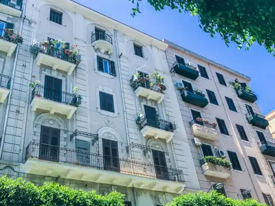 a tall white building with balconies and flower boxes at Sammartino suite in Palermo