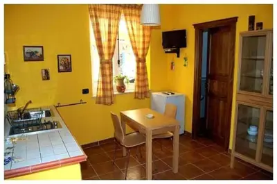a kitchen with yellow walls and a table and a sink at Le Tre Caravelle in Trabia