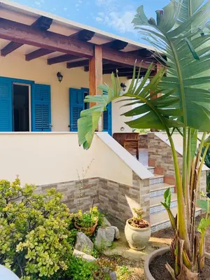 a house with blue shutters and a plant at Villa Ancora B&B in San Vito lo Capo