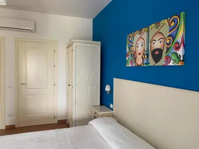 a blue room with a bed and a painting on the wall at Villa Ancora B&B in San Vito lo Capo