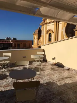 a patio with a table and chairs and a building at Ai Gradini Affittacamere in Castellammare del Golfo