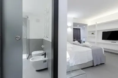 a white bathroom with a bed and a shower at Suite Palermo Apartment in Palermo