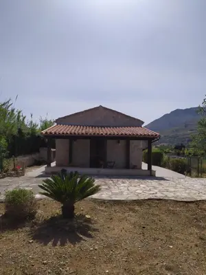 a small pavilion with a palm tree in front of it at Antico Rustico in Scopello