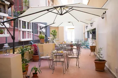 a patio with tables and chairs under a large umbrella at Bagnasco 18 suite&terrace in Palermo
