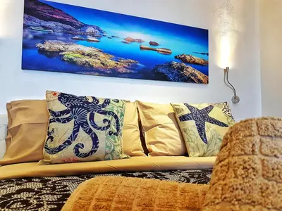 a couch with pillows and a painting on the wall at Brezza Marina Guesthouse in Cefalù
