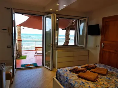 a bedroom with a bed and a view of the ocean at Brezza Marina Guesthouse in Cefalù