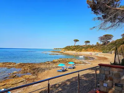 a beach with chairs and umbrellas on the sand at Brezza Marina Guesthouse in Cefalù