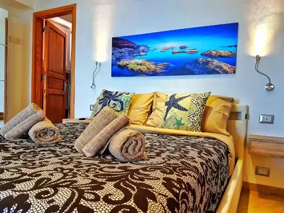 a bedroom with a bed with a painting on the wall at Brezza Marina Guesthouse in Cefalù