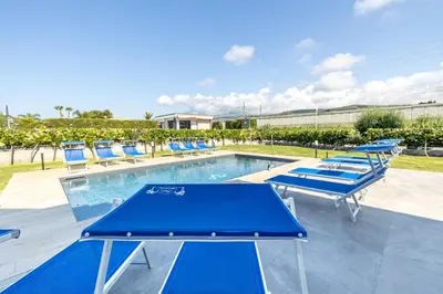 a pool with blue chairs and a ping pong table at Villa Arvilla with Private POOL in Campofelice di Roccella