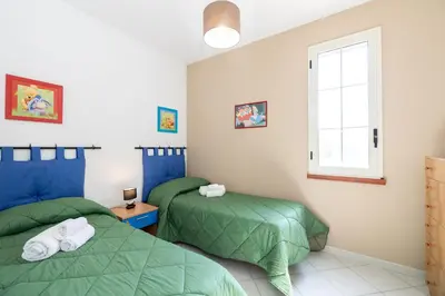 a bedroom with two green beds and a window at Villa Arvilla with Private POOL in Campofelice di Roccella