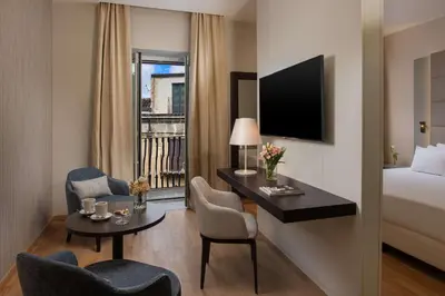 a hotel room with a bed and a desk and chairs at NH Collection Palermo Palazzo Sitano in Palermo
