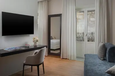 a living room with a couch and a television on a wall at NH Collection Palermo Palazzo Sitano in Palermo