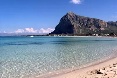 a view of a beach with a mountain in the background at Coral sea in San Vito lo Capo